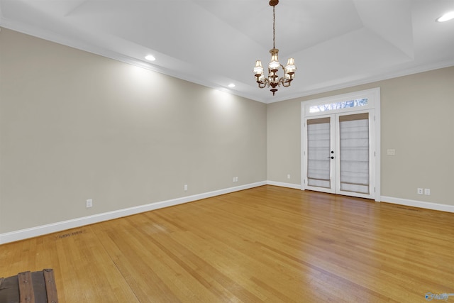 spare room featuring ornamental molding, light hardwood / wood-style flooring, french doors, and a notable chandelier