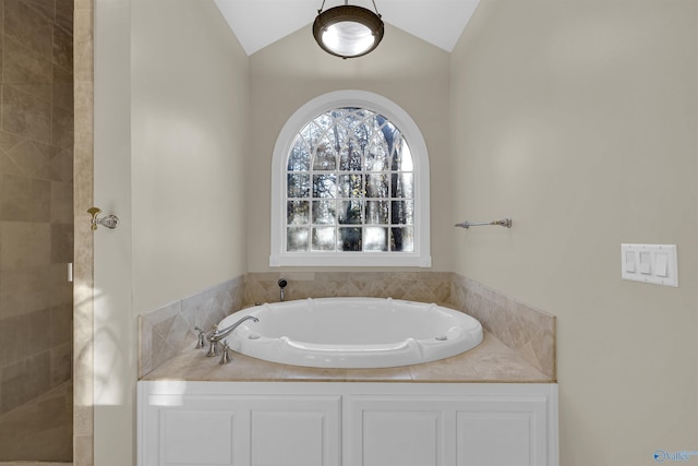 bathroom featuring lofted ceiling and a bath