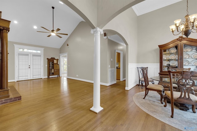 dining space with high vaulted ceiling, ceiling fan with notable chandelier, and hardwood / wood-style flooring