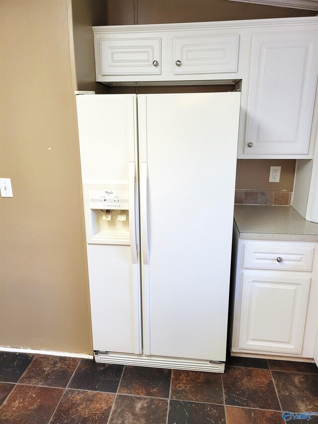 kitchen featuring white cabinetry and white refrigerator with ice dispenser