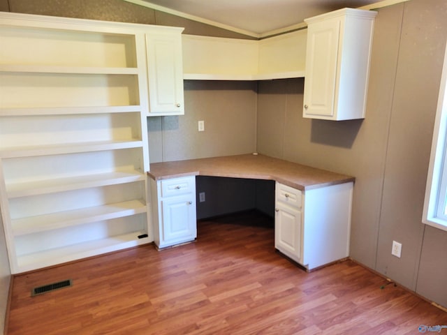 unfurnished office featuring built in desk, lofted ceiling, and light hardwood / wood-style floors