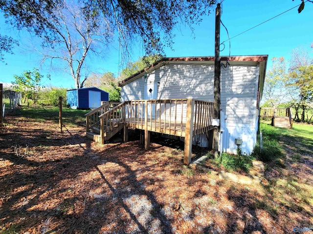 back of house featuring a storage shed and a wooden deck