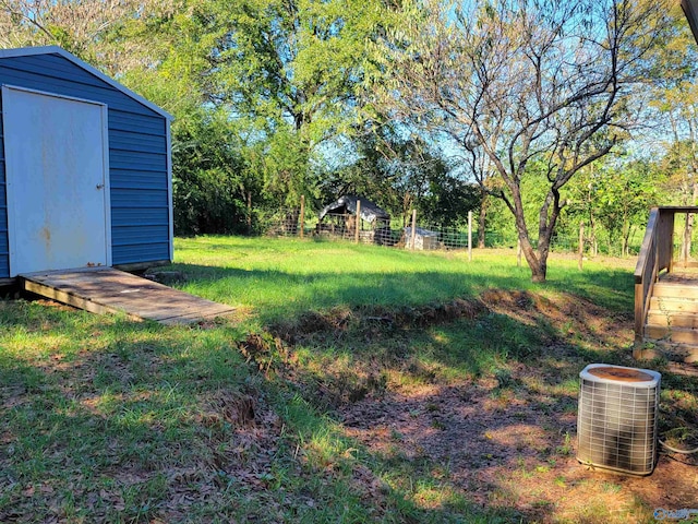 view of yard featuring a shed and central AC