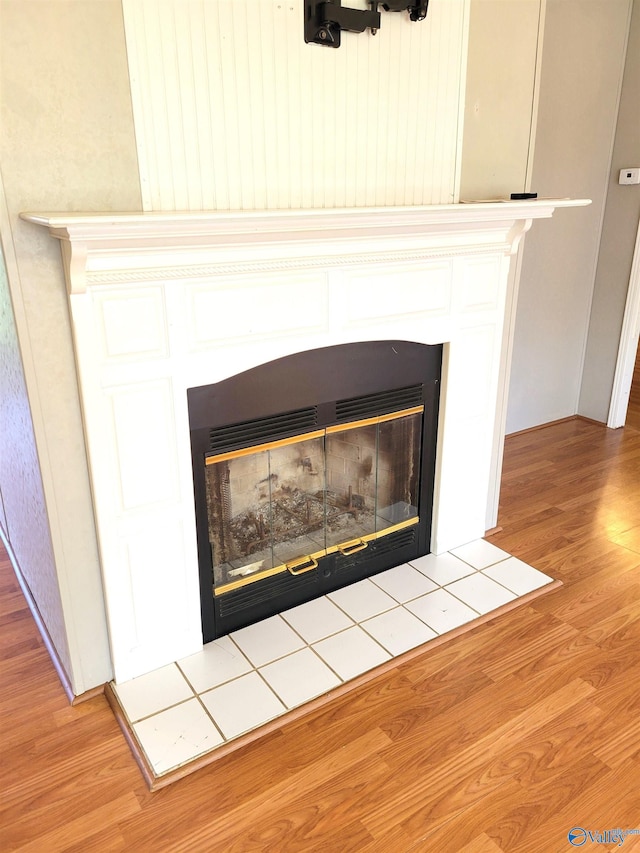 details with wood-type flooring and a tiled fireplace