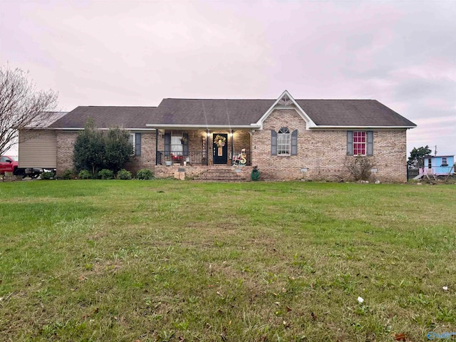 ranch-style home with covered porch and a yard