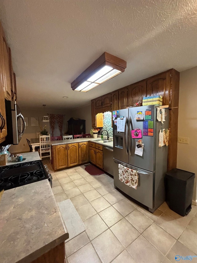 kitchen featuring sink, light tile patterned flooring, stainless steel appliances, and a textured ceiling