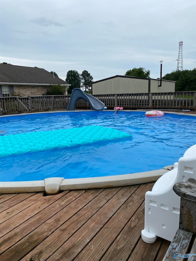 view of swimming pool with a water slide and a deck