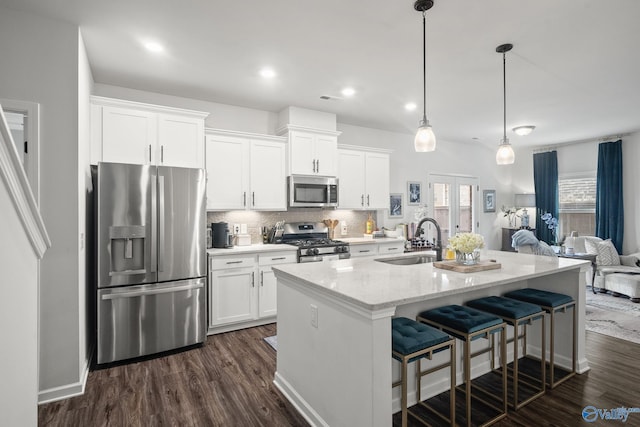kitchen featuring a sink, stainless steel appliances, tasteful backsplash, white cabinetry, and dark wood finished floors