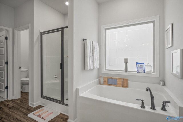 full bath with toilet, wood finished floors, a shower stall, and a garden tub