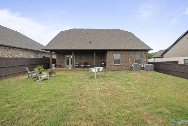back of house featuring central AC, brick siding, a fenced backyard, and a lawn