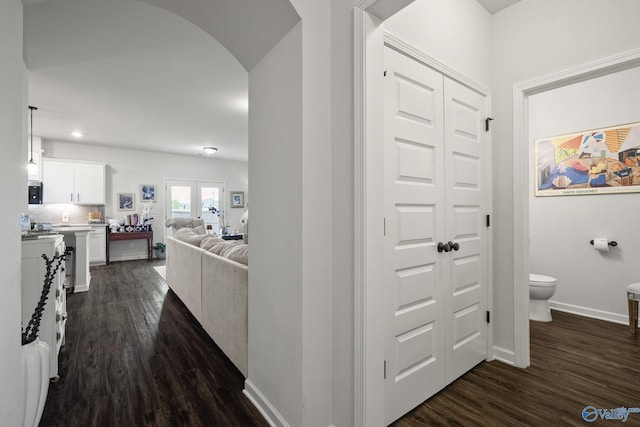corridor featuring baseboards, recessed lighting, arched walkways, and dark wood-type flooring