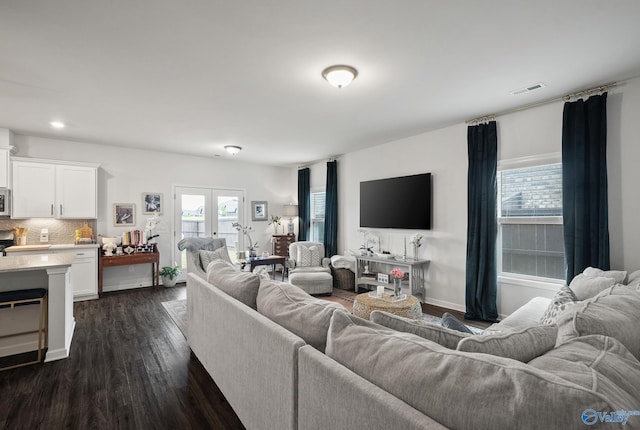 living room with dark wood-style flooring, visible vents, and baseboards