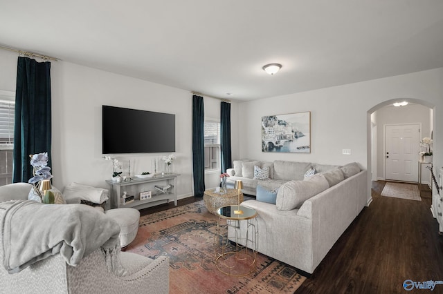 living room with baseboards, dark wood-style floors, and arched walkways