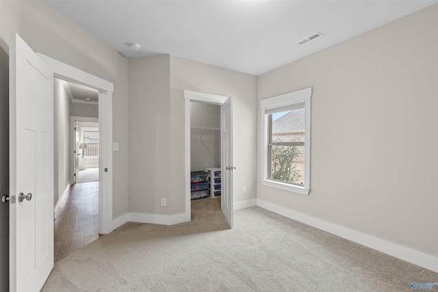 unfurnished bedroom featuring light colored carpet, a spacious closet, and a closet