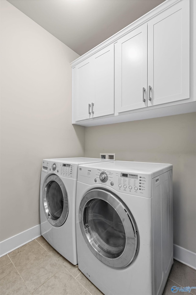 clothes washing area featuring light tile patterned floors, cabinets, and washing machine and clothes dryer