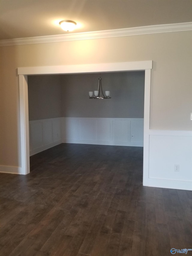 empty room with ornamental molding, a notable chandelier, and dark hardwood / wood-style flooring