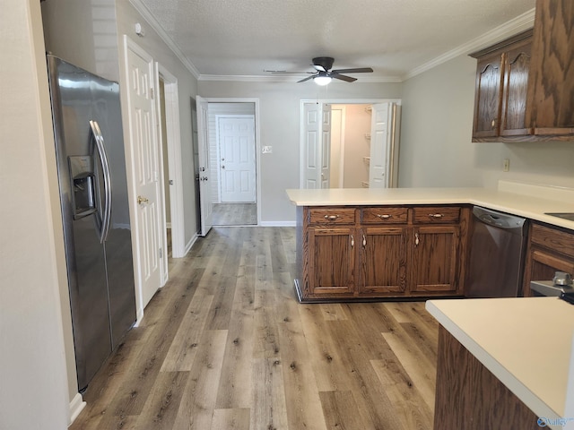 kitchen with a peninsula, stainless steel appliances, crown molding, and light countertops