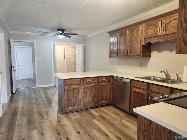 kitchen featuring light wood finished floors, light countertops, a peninsula, stainless steel dishwasher, and a sink