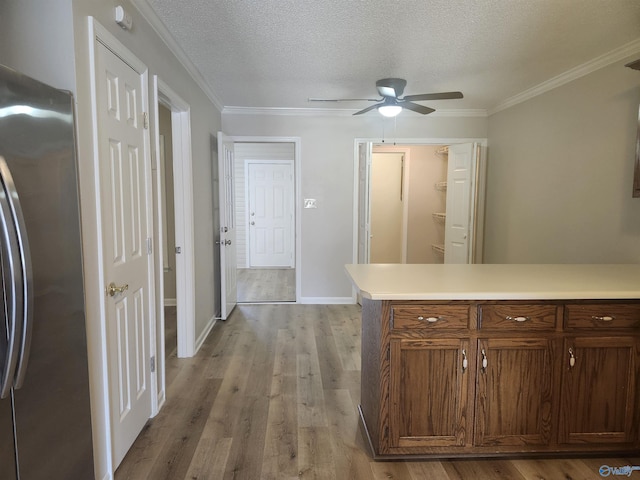 kitchen with a textured ceiling, light wood-type flooring, freestanding refrigerator, and light countertops