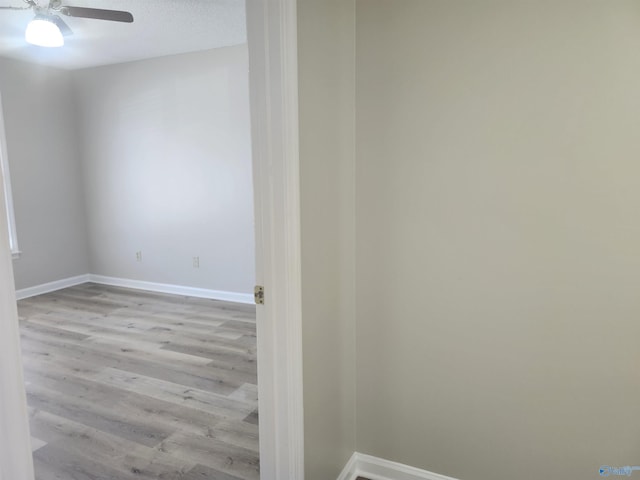 empty room featuring wood finished floors, a ceiling fan, baseboards, and a textured ceiling