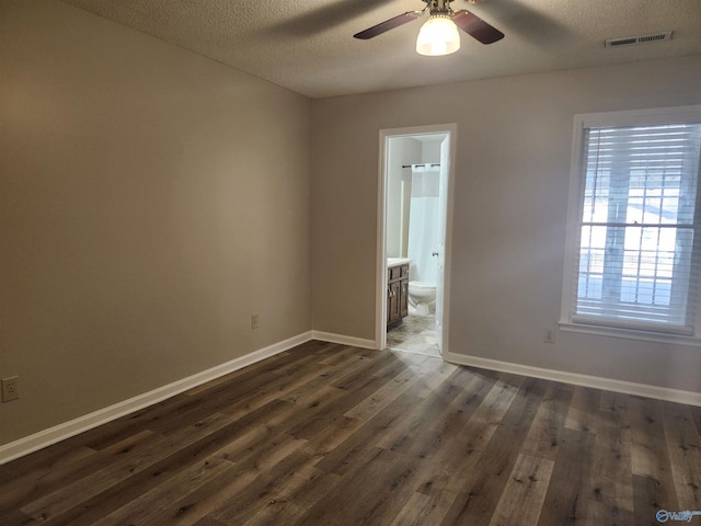 unfurnished room with visible vents, dark wood-type flooring, a textured ceiling, baseboards, and ceiling fan