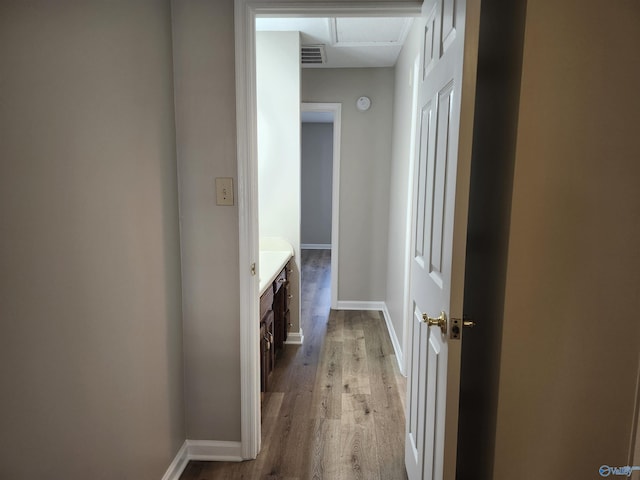 corridor with visible vents, baseboards, and wood finished floors