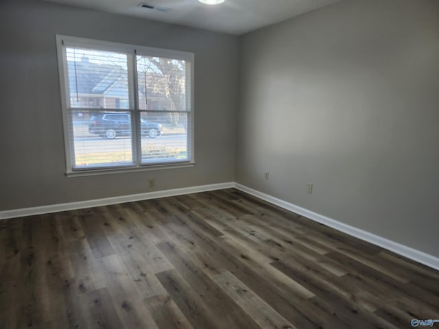 unfurnished room with baseboards, plenty of natural light, and dark wood-style flooring