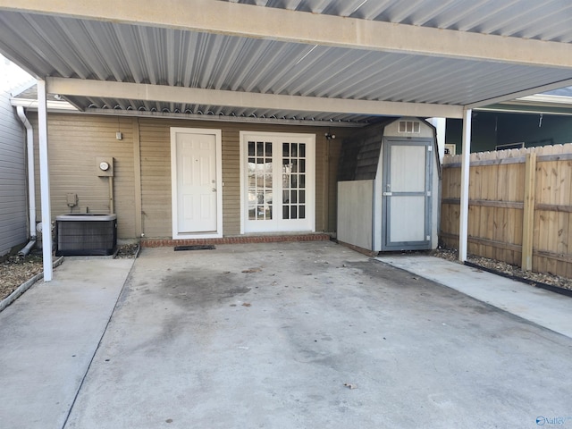 view of patio featuring cooling unit, fence, an outdoor structure, a carport, and a storage unit