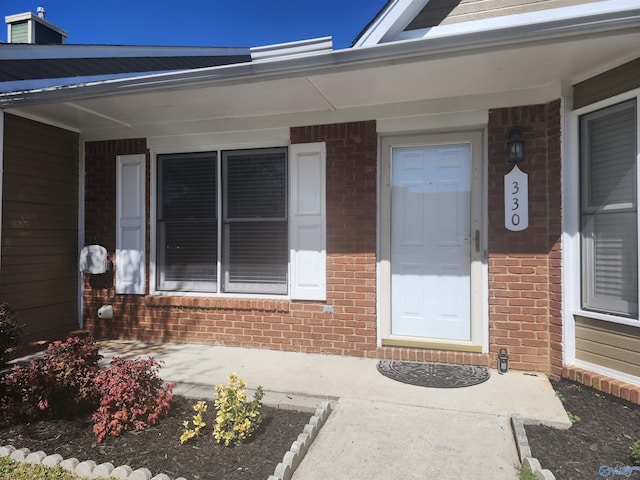 doorway to property featuring brick siding and a porch