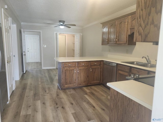 kitchen with stainless steel dishwasher, a peninsula, light countertops, and a sink