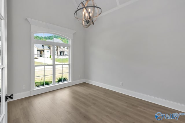 spare room with dark hardwood / wood-style flooring and an inviting chandelier