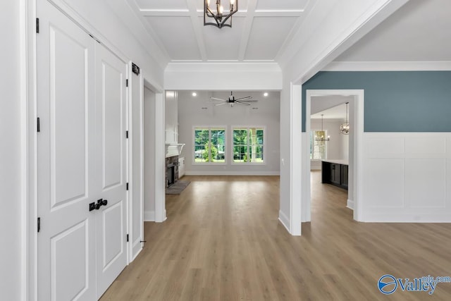 hallway featuring crown molding, coffered ceiling, a chandelier, and light hardwood / wood-style floors