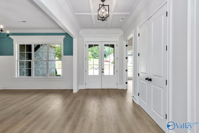 entrance foyer featuring light wood-type flooring, coffered ceiling, a chandelier, and french doors