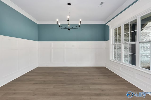 unfurnished dining area with an inviting chandelier, ornamental molding, and dark hardwood / wood-style floors