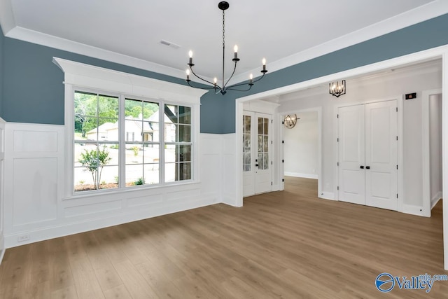 unfurnished dining area with wood-type flooring, ornamental molding, and a chandelier