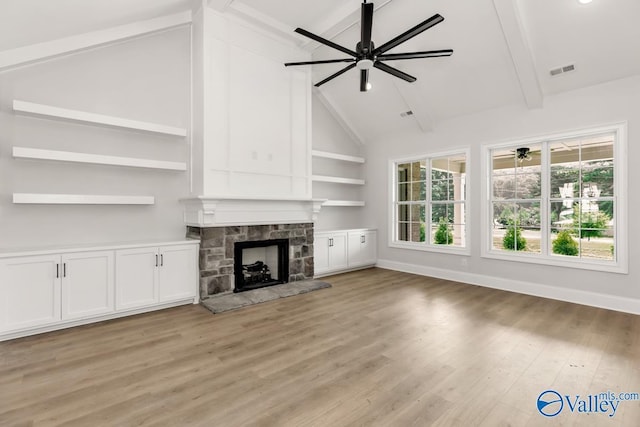 unfurnished living room featuring ceiling fan, a fireplace, lofted ceiling with beams, and light hardwood / wood-style flooring