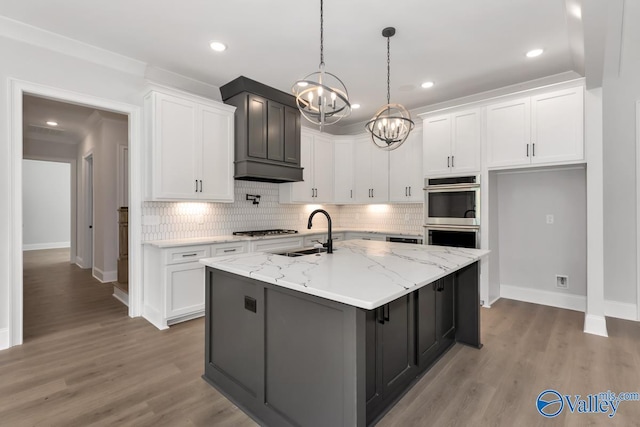 kitchen featuring a center island with sink and white cabinets