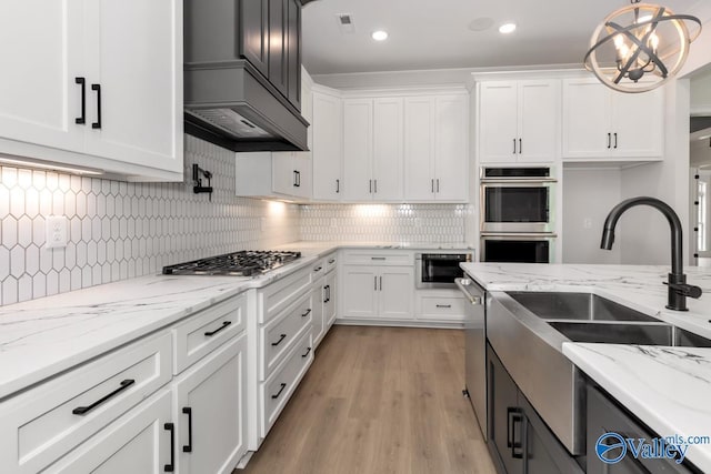 kitchen with pendant lighting, sink, white cabinets, stainless steel appliances, and light stone countertops