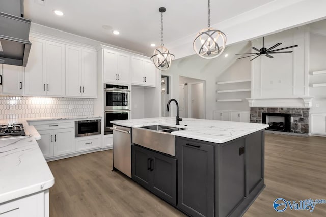 kitchen with sink, appliances with stainless steel finishes, white cabinets, a center island with sink, and decorative light fixtures