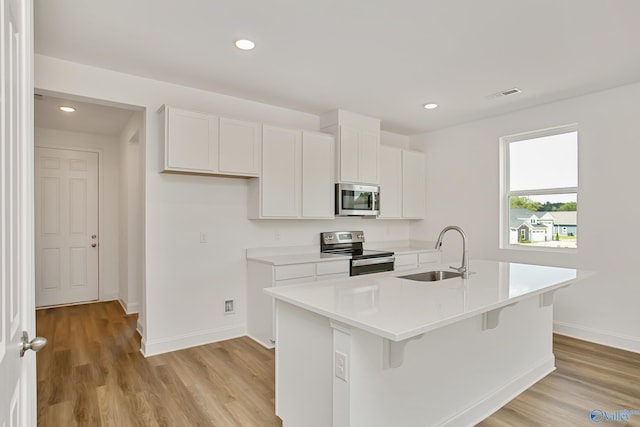 kitchen featuring white cabinetry, sink, a kitchen island with sink, stainless steel appliances, and light hardwood / wood-style flooring