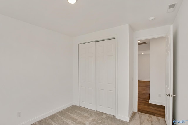 unfurnished bedroom featuring light carpet and a closet