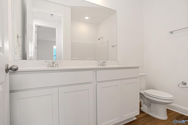 bathroom featuring hardwood / wood-style flooring, a shower, vanity, and toilet