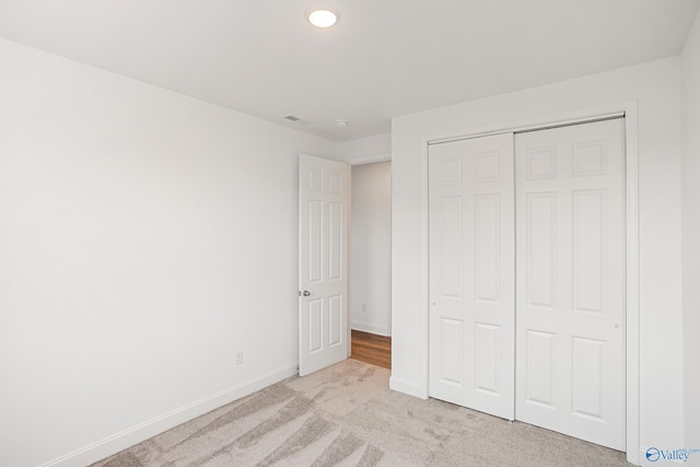 unfurnished bedroom with light colored carpet and a closet