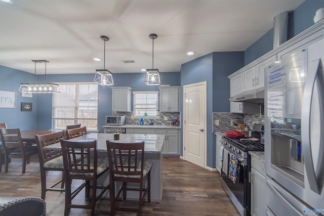 kitchen with pendant lighting, stainless steel appliances, a kitchen breakfast bar, and a kitchen island