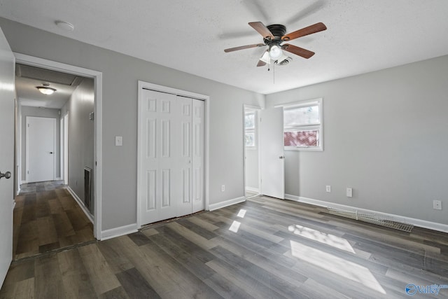 unfurnished bedroom with a closet, ceiling fan, a textured ceiling, and dark hardwood / wood-style floors