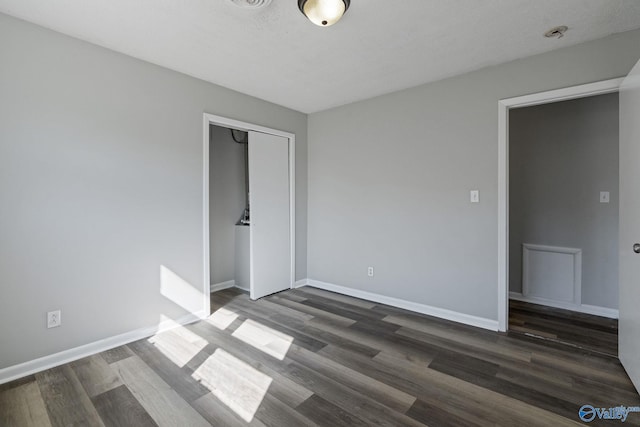 unfurnished bedroom with dark hardwood / wood-style floors and a closet