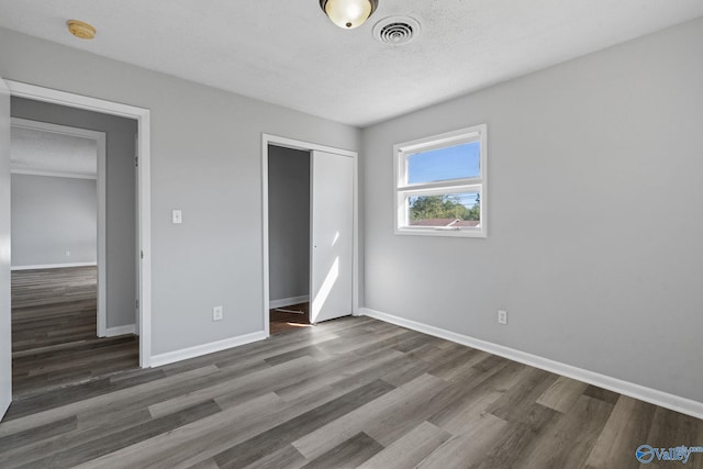 unfurnished bedroom featuring a closet, a textured ceiling, and dark hardwood / wood-style flooring