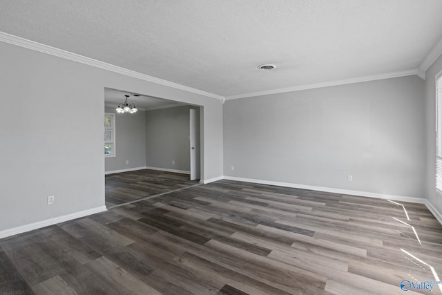 spare room featuring crown molding, dark hardwood / wood-style floors, and a chandelier