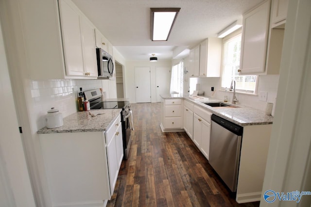 2520 Excalibur Dr SE, Huntsville, AL 35803 - kitchen with appliances with stainless steel finishes, a sink, dark wood-style floors, decorative backsplash, and white cabinetry