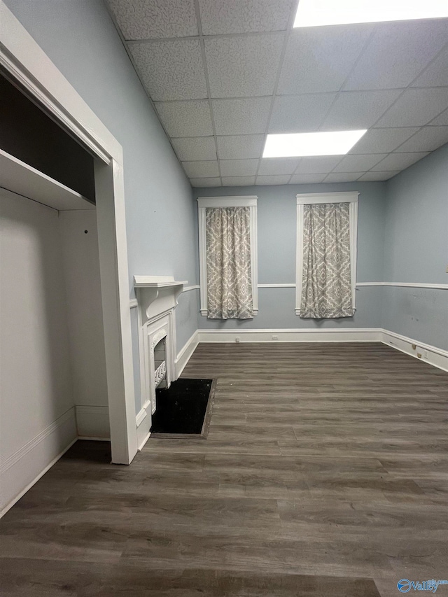 unfurnished living room featuring a paneled ceiling and dark wood-type flooring